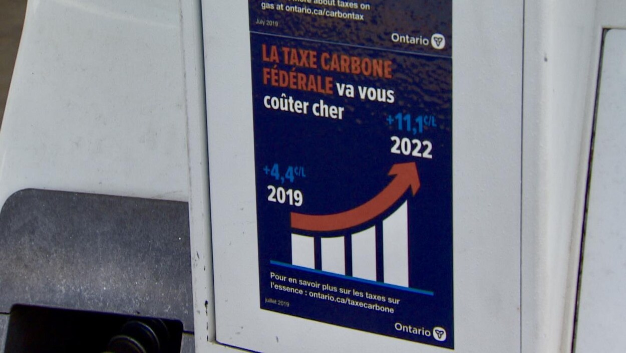 Un autocollant sur une pompe à essence. On peut y lire : « La taxe carbone fédérale va vous coûter cher ». Le logo de l'Ontario est imprimé en bas à droite de l'autocollant.