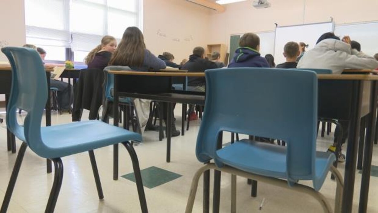 Une salle de classe et des élèves, assis, de dos.