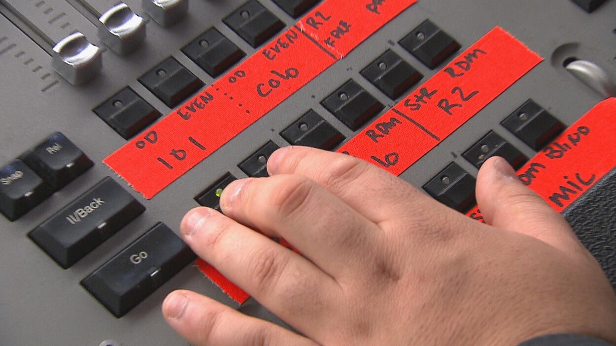 La main d'un technicien de scène appuie sur des boutons.