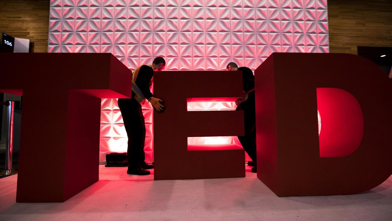 Des hommes placent les lettres T E D en trois dimensions Des hommes placent les lettres T E D en trois dimensions