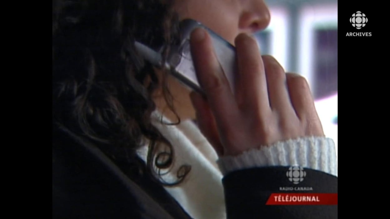 Une femme porte un téléphone cellulaire à son oreille.