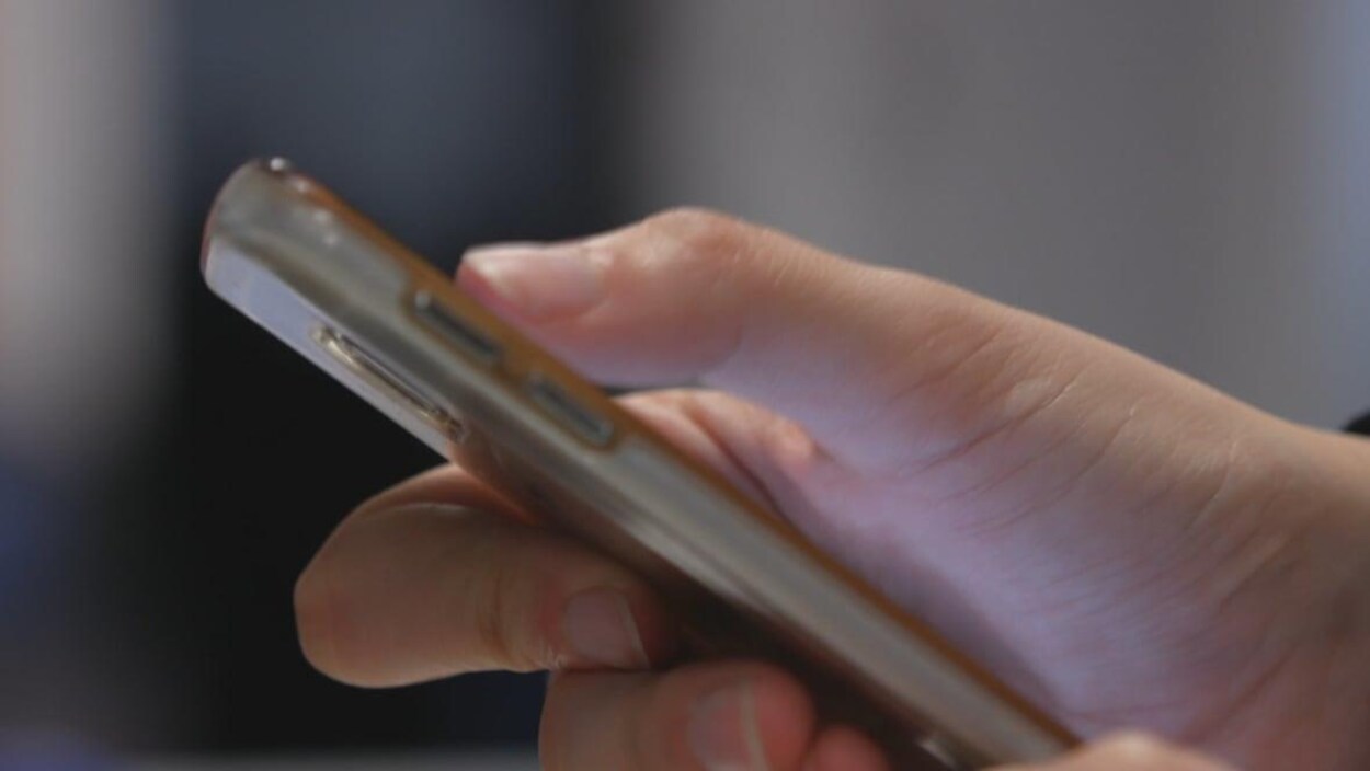 Une personne tient en main un téléphone intelligent.