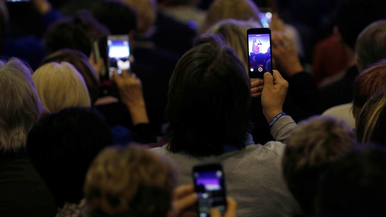 Des participants à un rassemblement du candidat François Fillon en France prennent des images avec leur téléphone.