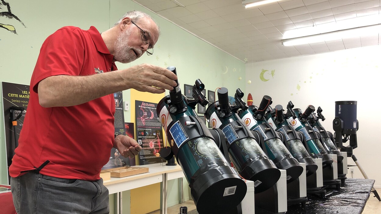 Claude Boivin regarde de près un télescope.