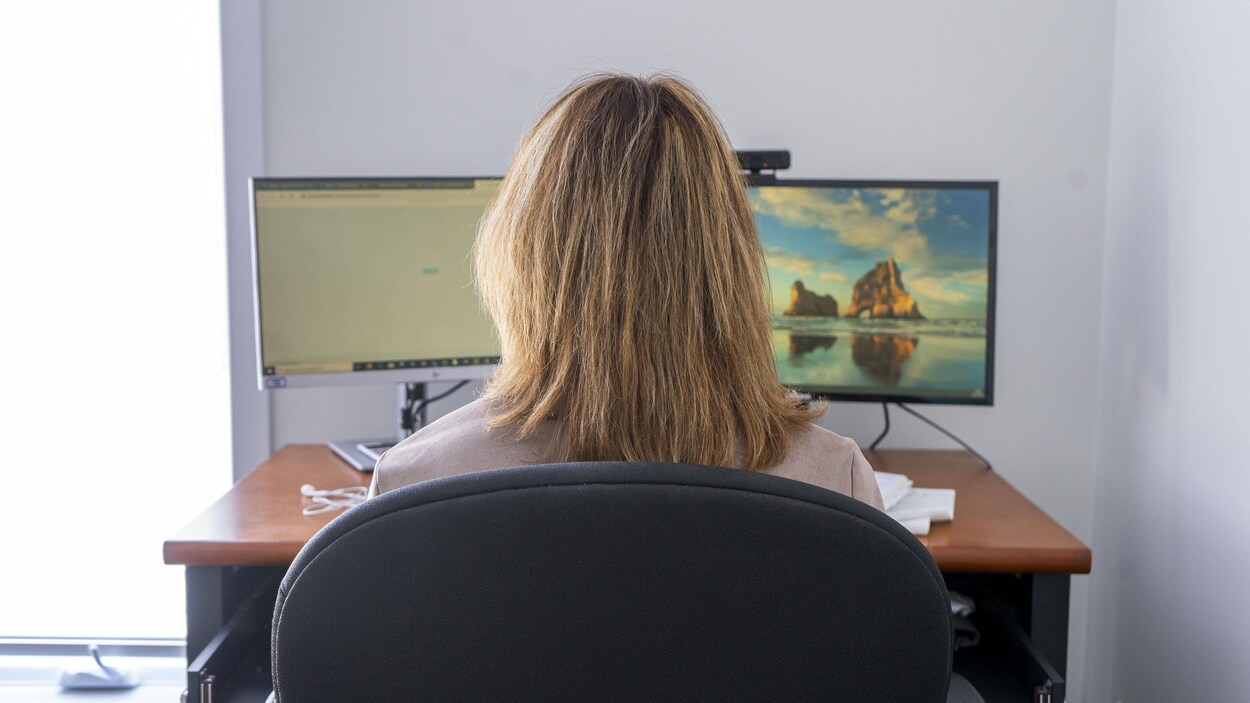 Une femme est assise devant deux écrans d'ordinateur.