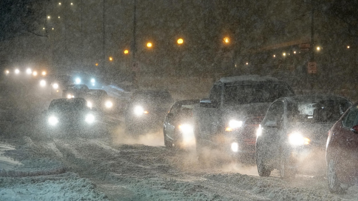 Des voitures à la queue leu leu sous la neige.