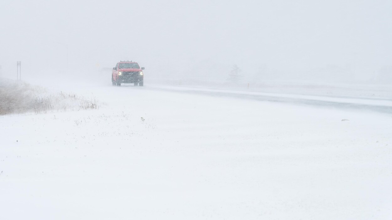 Un camion roule sur une route enneigée.