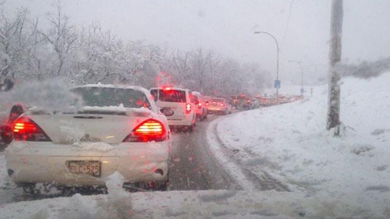 Plusieurs voitures bloquées sur une route lors d'une tempête de neige.