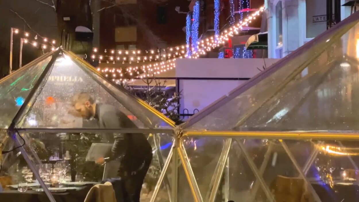 Un serveur penché au-dessus d'une table dans un dôme transparent
