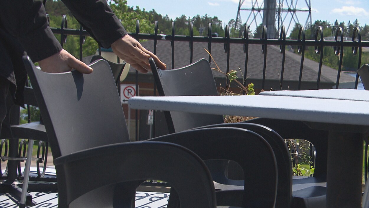 Des mains placent des chaises autour d'une table.