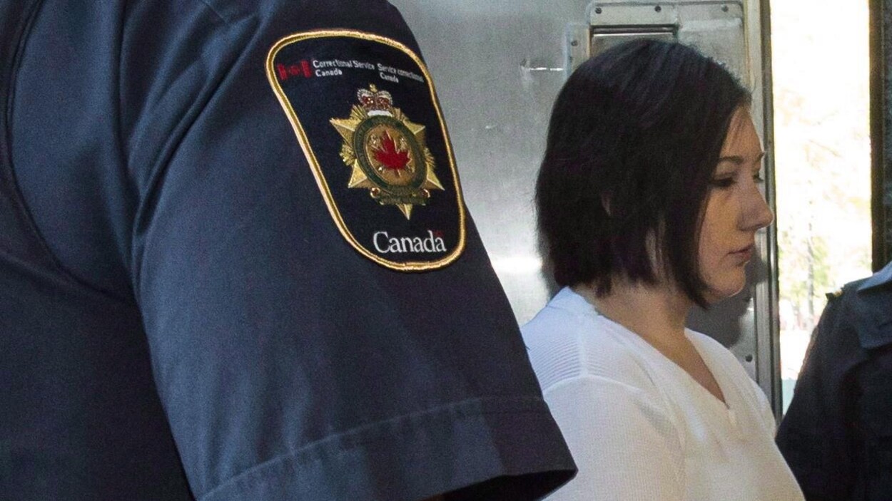 Une femme habillée en blanc est escortée par des agents de Service correctionnel Canada.