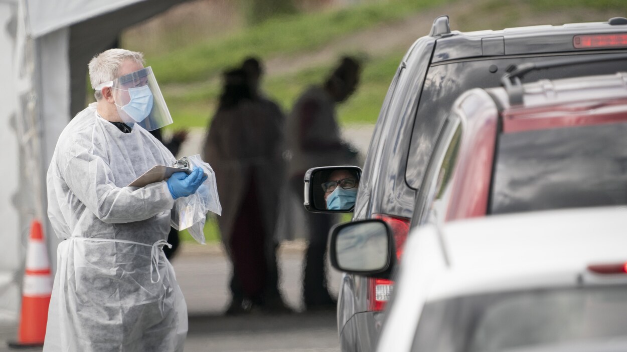 Un préposé accueille des automobilistes venus passer un test de dépistage à la COVID-19.