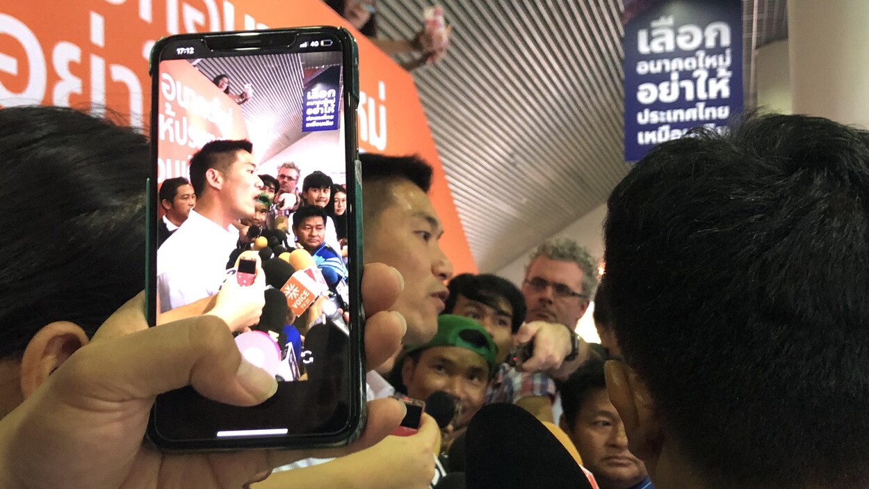 Une personne prend une photo d'un homme politique à l'aide d'un téléphone intelligent.