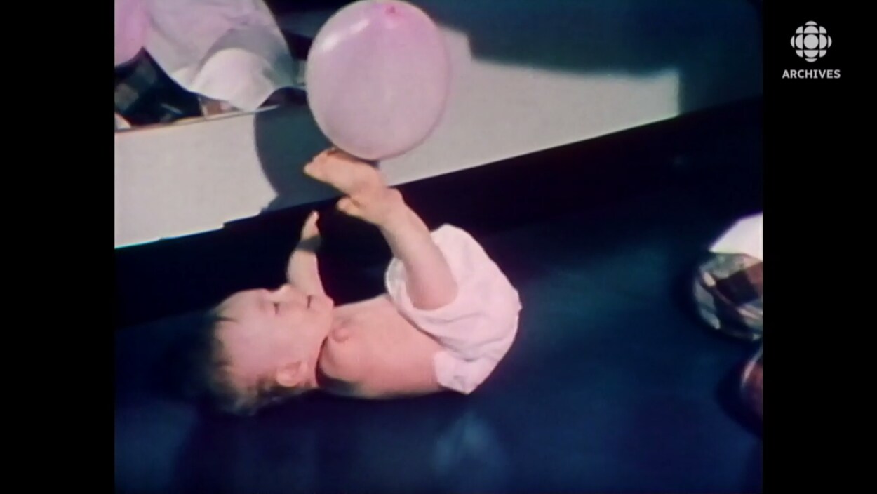 Un enfant avec des malformations aux bras et aux jambes jouent au sol avec un ballon.