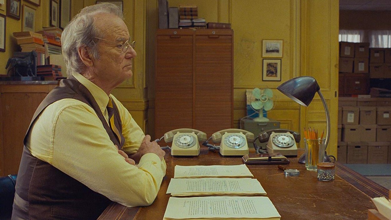 L'homme est assis à son bureau avec trois téléphones.