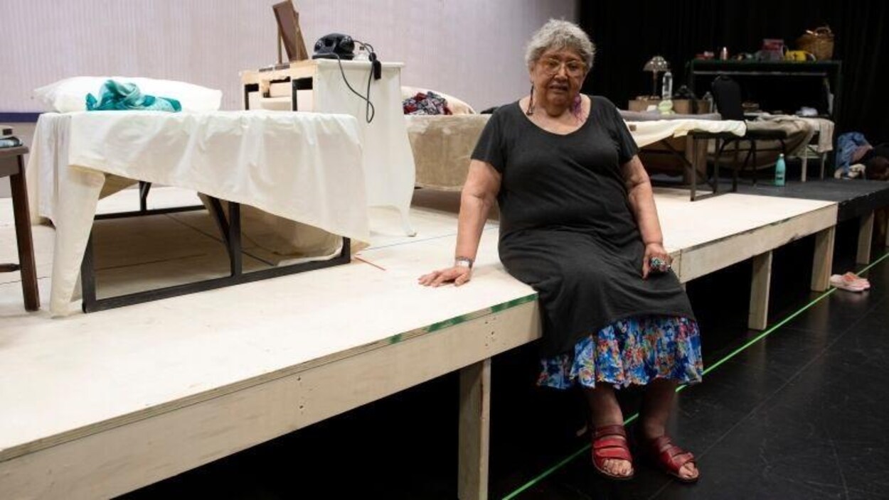 Muriel Miguel est assise sur une scène.