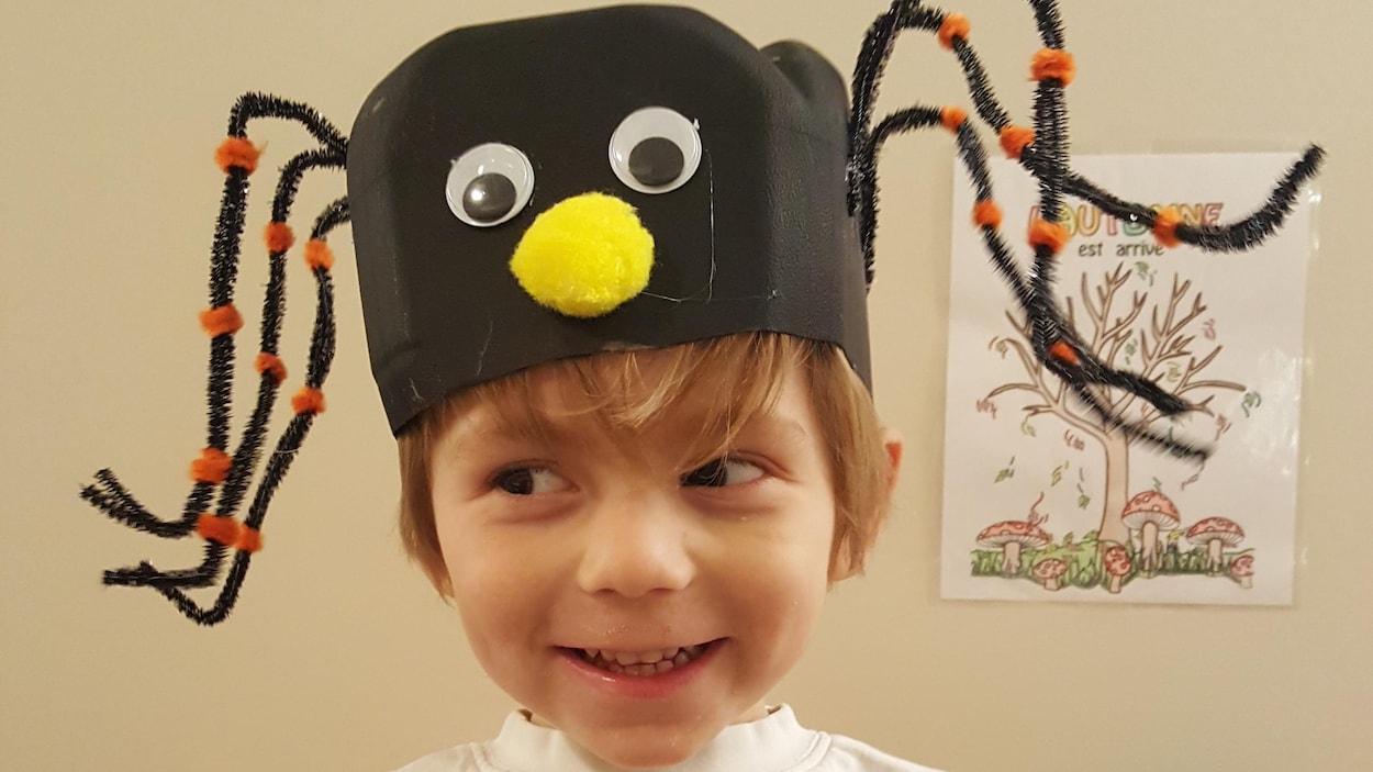 Theo souriant avec un chapeau bricolé lors d'une activité.