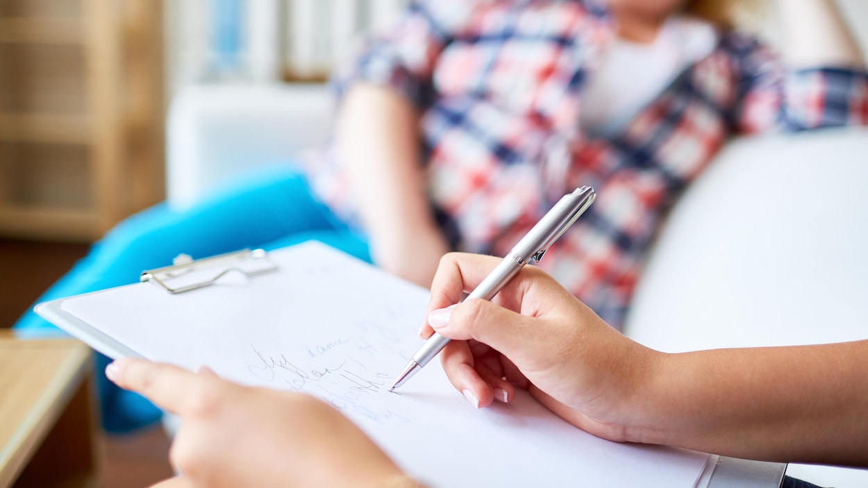 Une thérapeute prend des notes pendant qu'une cliente se confie.