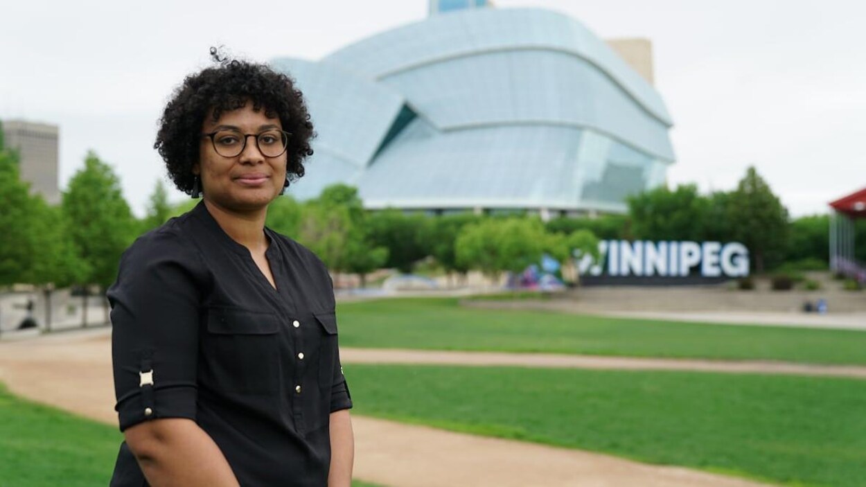 Une femme avec le Musée canadien pour les droits de la personne derrière elle.
