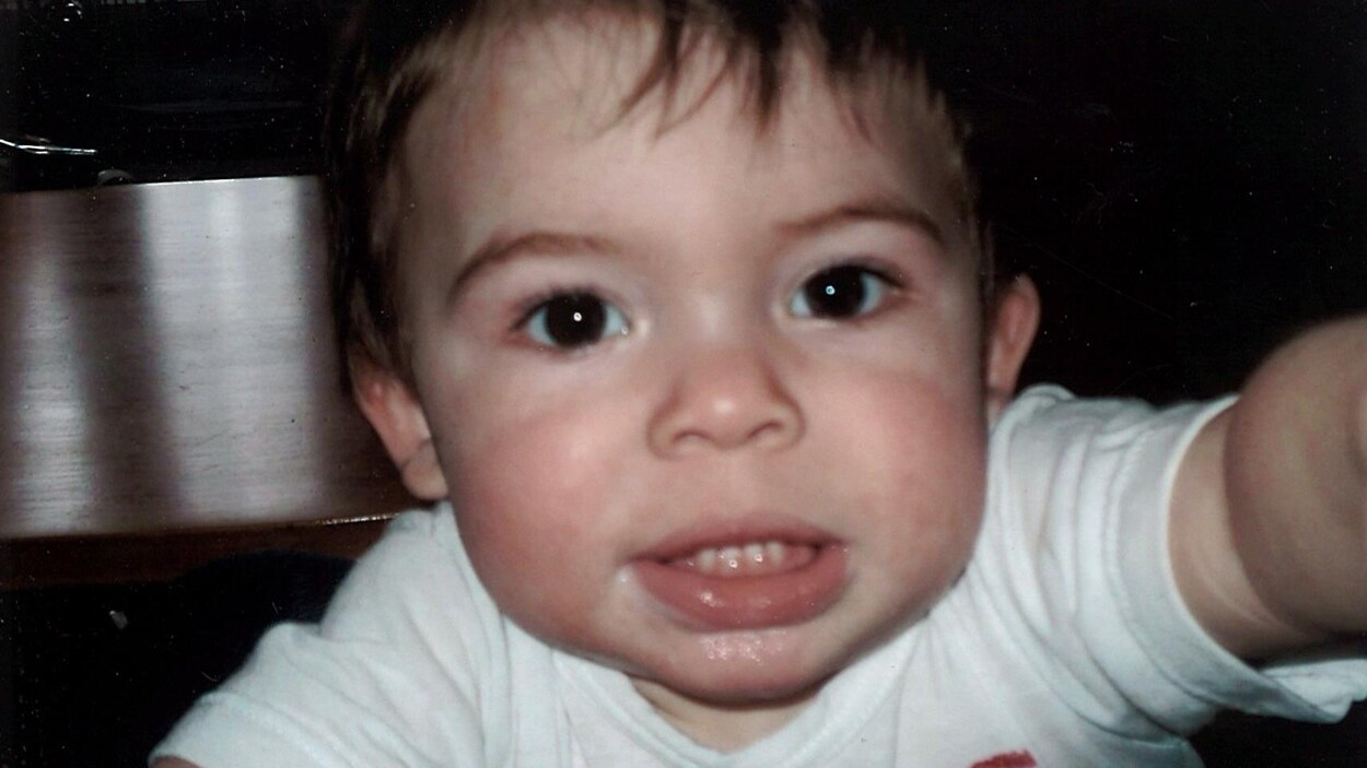 Un bébé tend le bras devant lui.