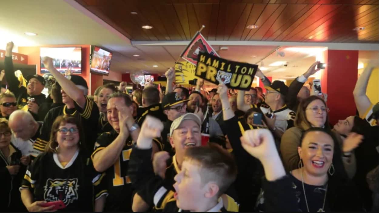 Des amateurs habillés aux couleurs des Tiger Cats festoient ensemble.