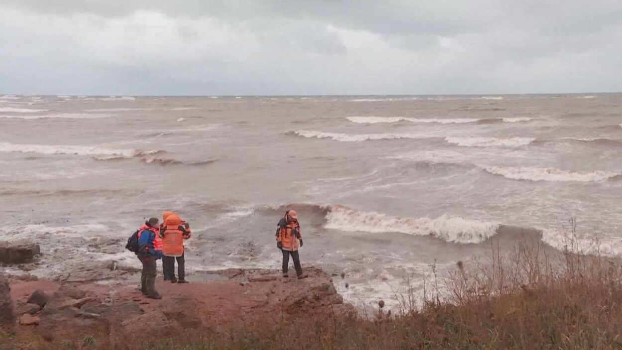 Trois personnes sur la côte regardent vers la mer