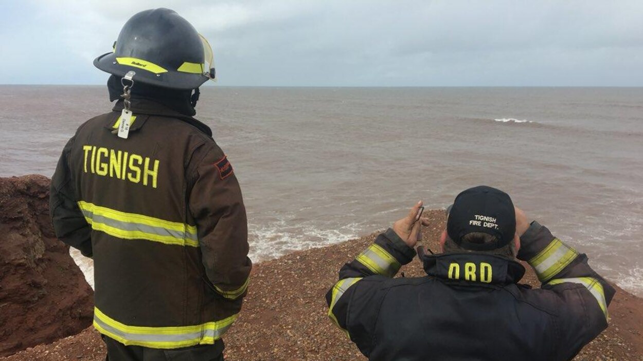 Deux pompiers scrutent la mer, l'un d'eux emploie des jumelles
