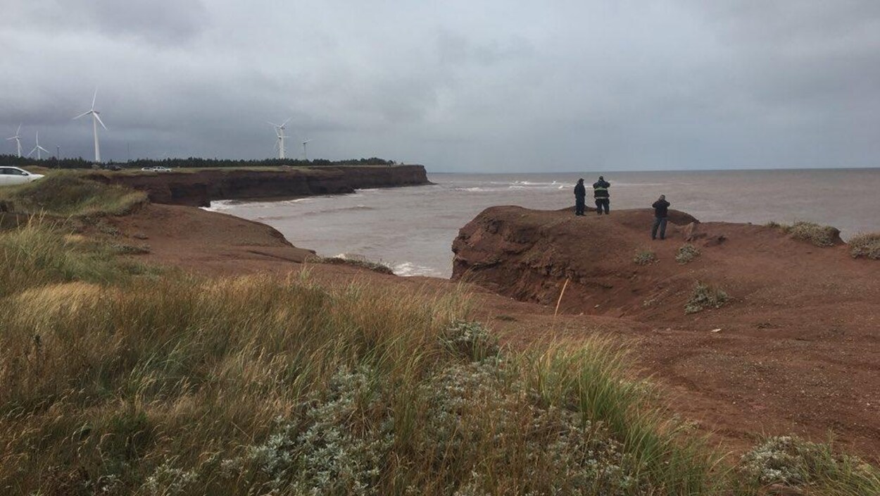 Trois personnes sur la côte regardent vers la mer