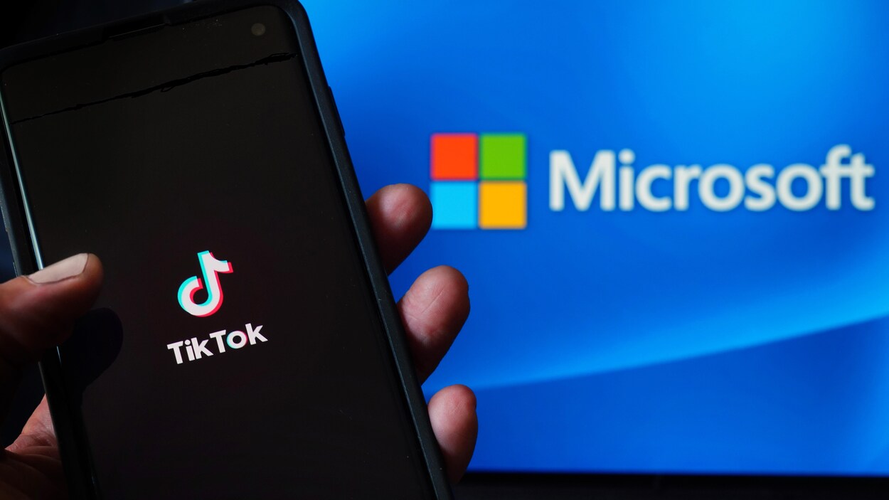 Un téléphone qui affiche le logo de TikTok, devant un écran qui affiche le logo de Microsoft.