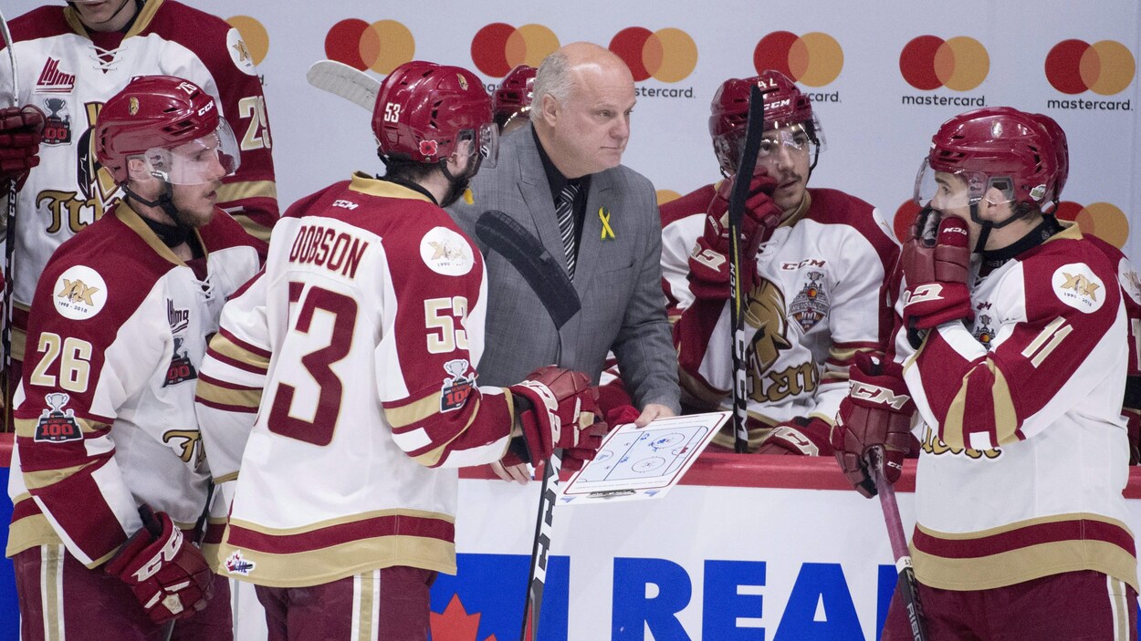Cinq hockeyeurs entourent leur entraîneur sur le banc des joueurs