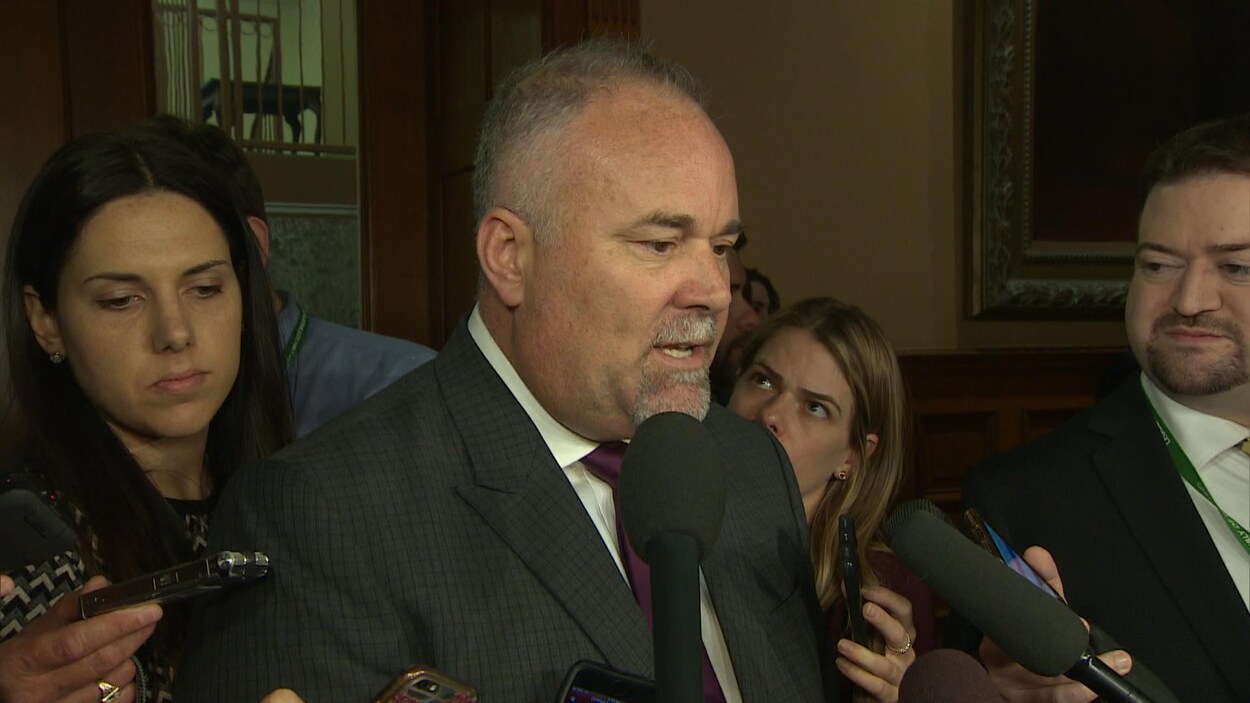 Le ministre Todd Smith devant les microphones des journalistes.
