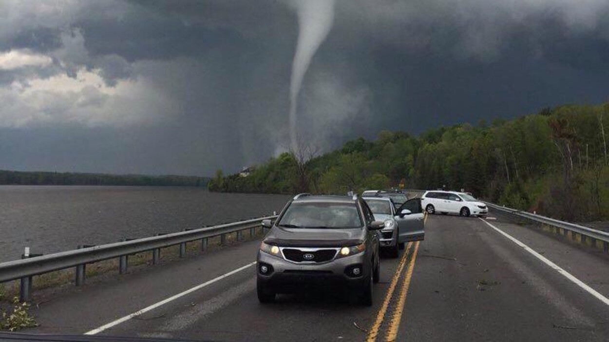 Une file de voitures devant une tornade.