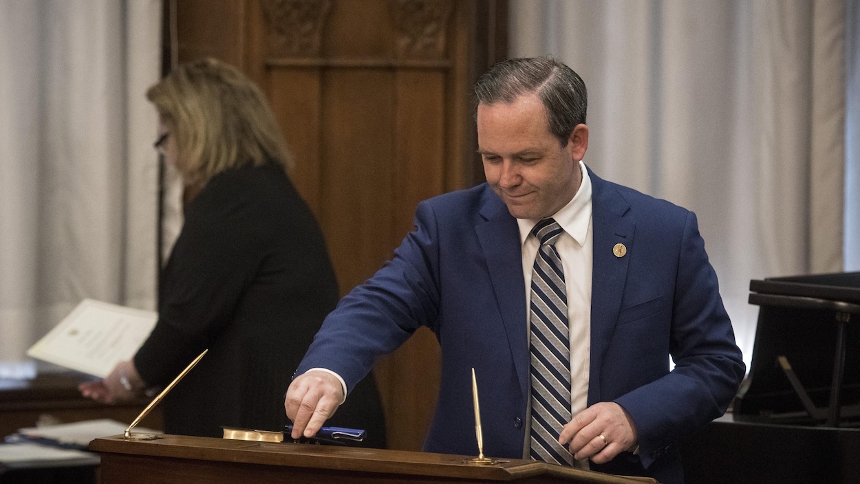 Doug Downey pose un stylo sur un pupitre dans une salle.