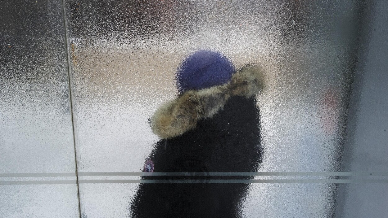 Un piéton attend un tramway dans un abri-bus glacé le long de la rue King Ouest pendant une tempête hivernale à Toronto le mardi 12 février 2019. LA PRESSE CANADIENNE / Tijana Martin