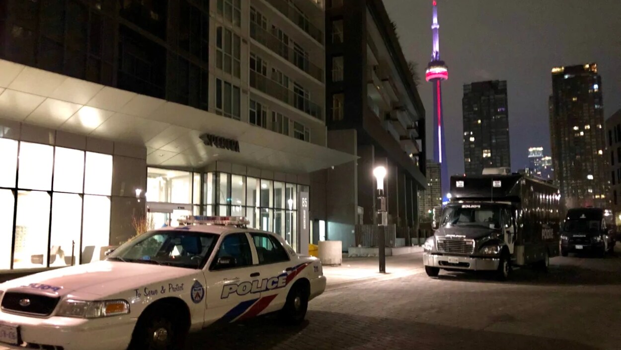 Des véhicules de la police de Toronto sont stationnés devant un immeuble de copropriété la nuit.