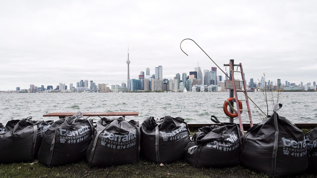 Des sacs de sable sur une des îles de Toronto et le centre-ville au loin.