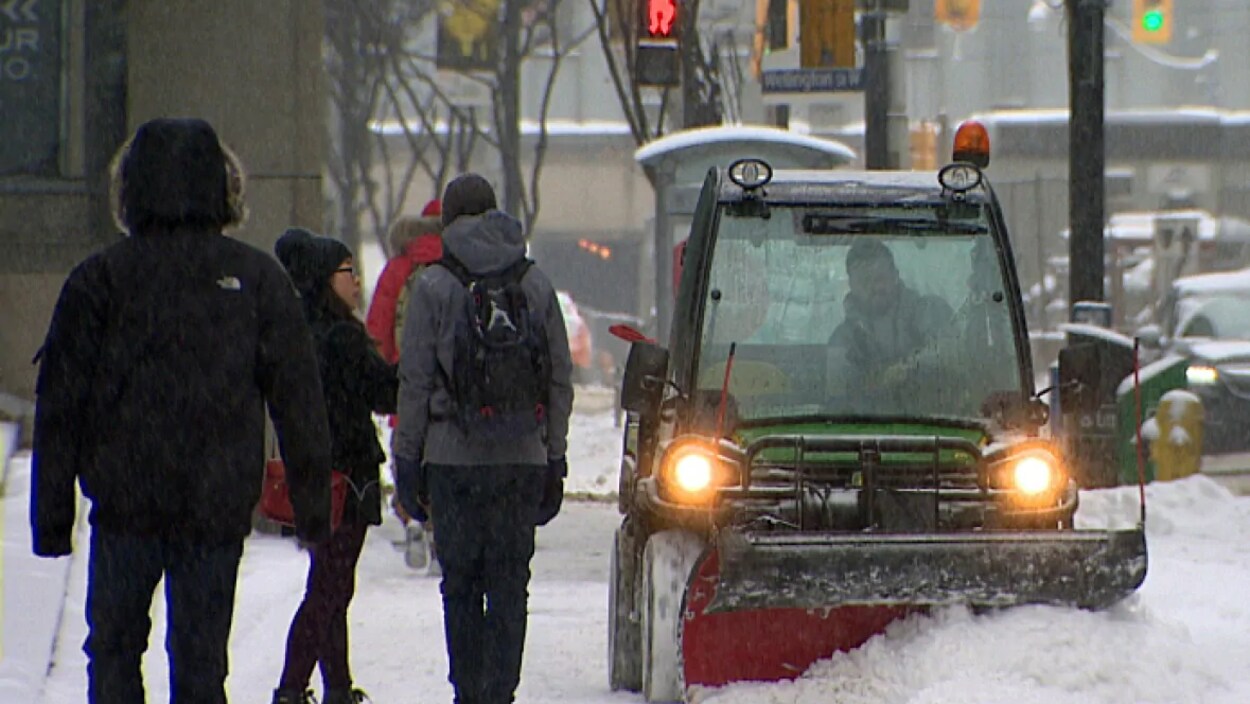Un chasse-neige en train de déneiger une voie dans la ville.