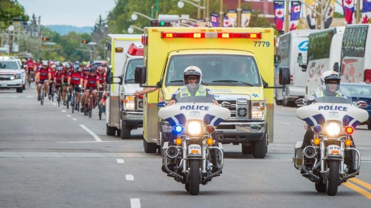 Deux motos de police suivies de deux ambulances et d'un peloton de cyclistes. Deux motos de police suivies de deux ambulances et d'un peloton de cyclistes.