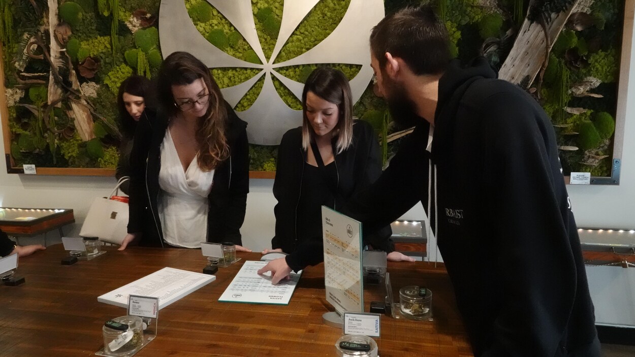 Deux femmes écoutent les conseils d'un vendeur dans un magasin de cannabis. 