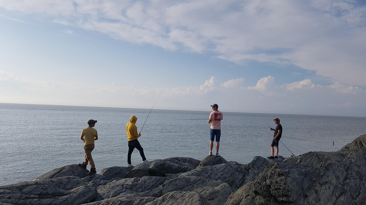 Des touristes pêchent sur le bord du fleuve à Rivière-du-Loup.