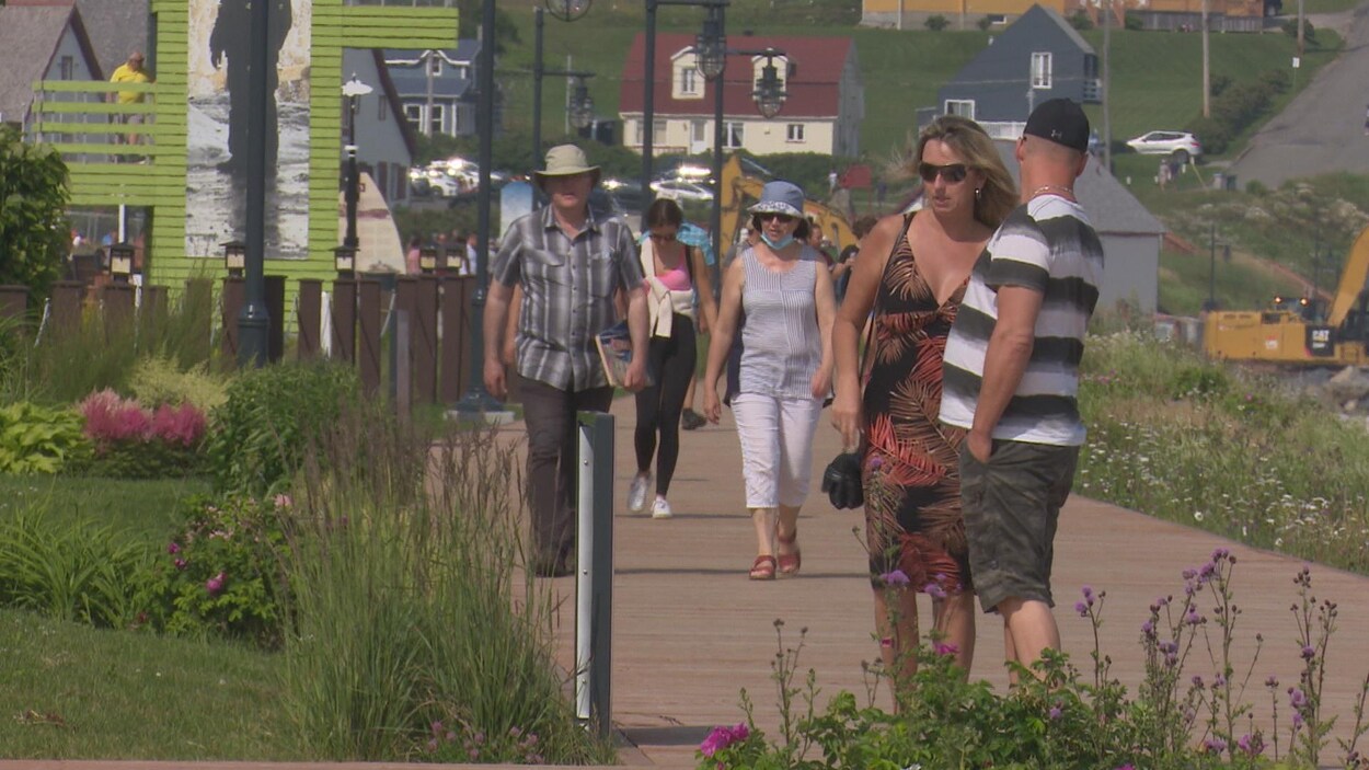 Des touristes marchent sur une promenade de bois à Percé.