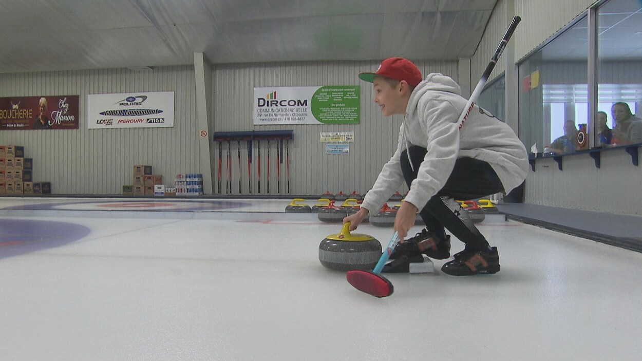 Un jeune joueur de curling lance sa pierre.