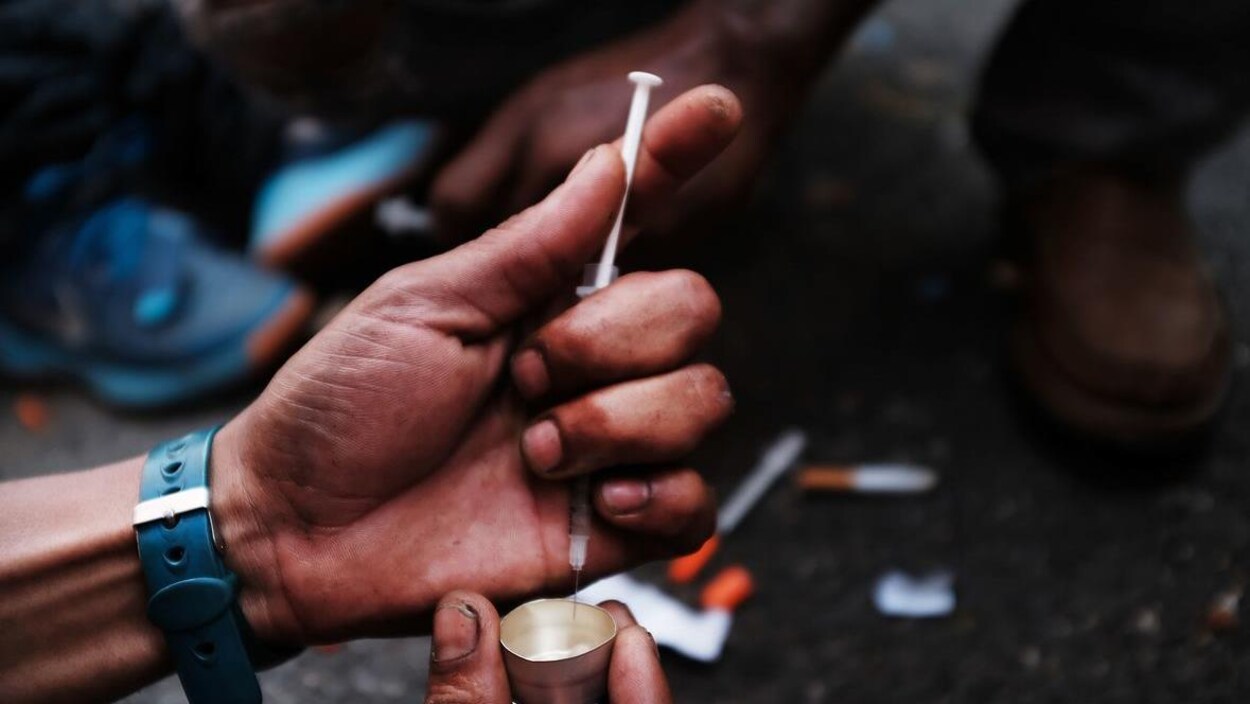Un toxicomane manipule une seringue.