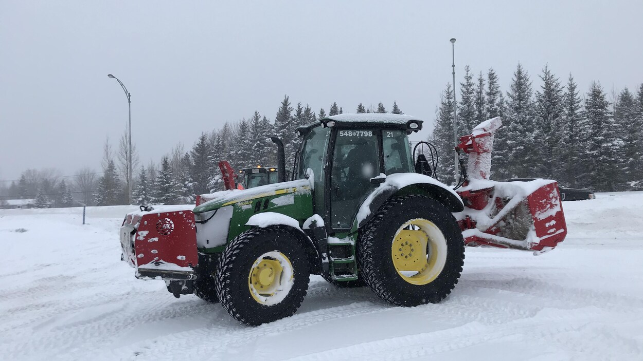 Un tracteur de déneigement se trouve dans un stationnement.