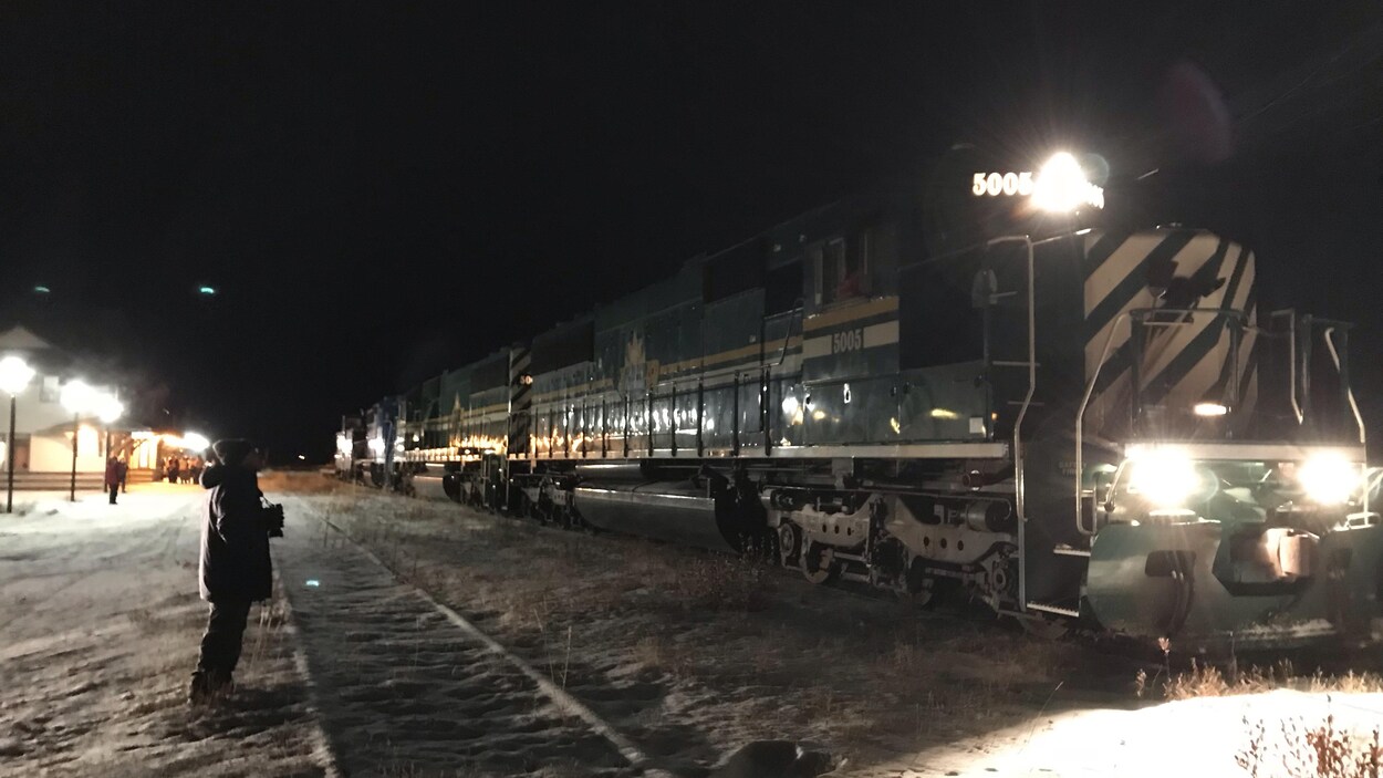 Sur des rails enneigés, un train est arrêté dans l'obscurité.