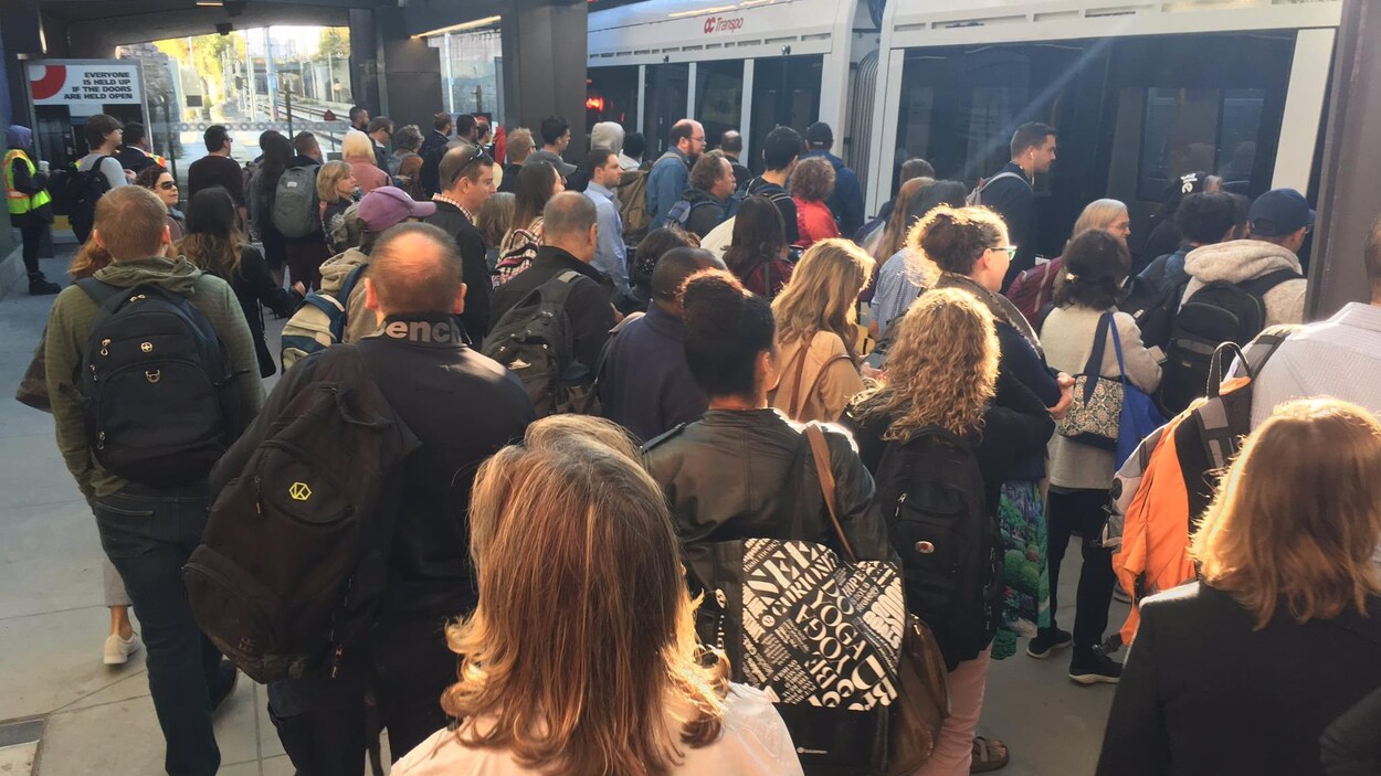 Des personnes se pressent pour monter à bord du train léger.