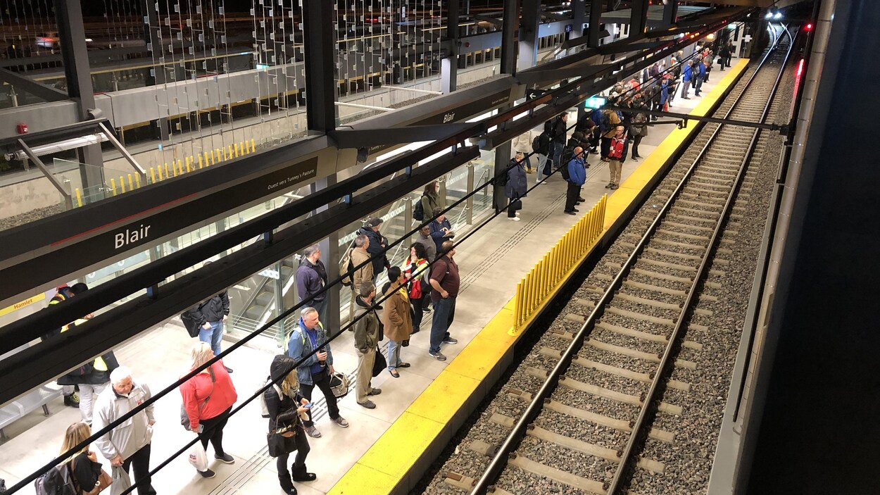 Des usagers attendent le train léger sur le quai.