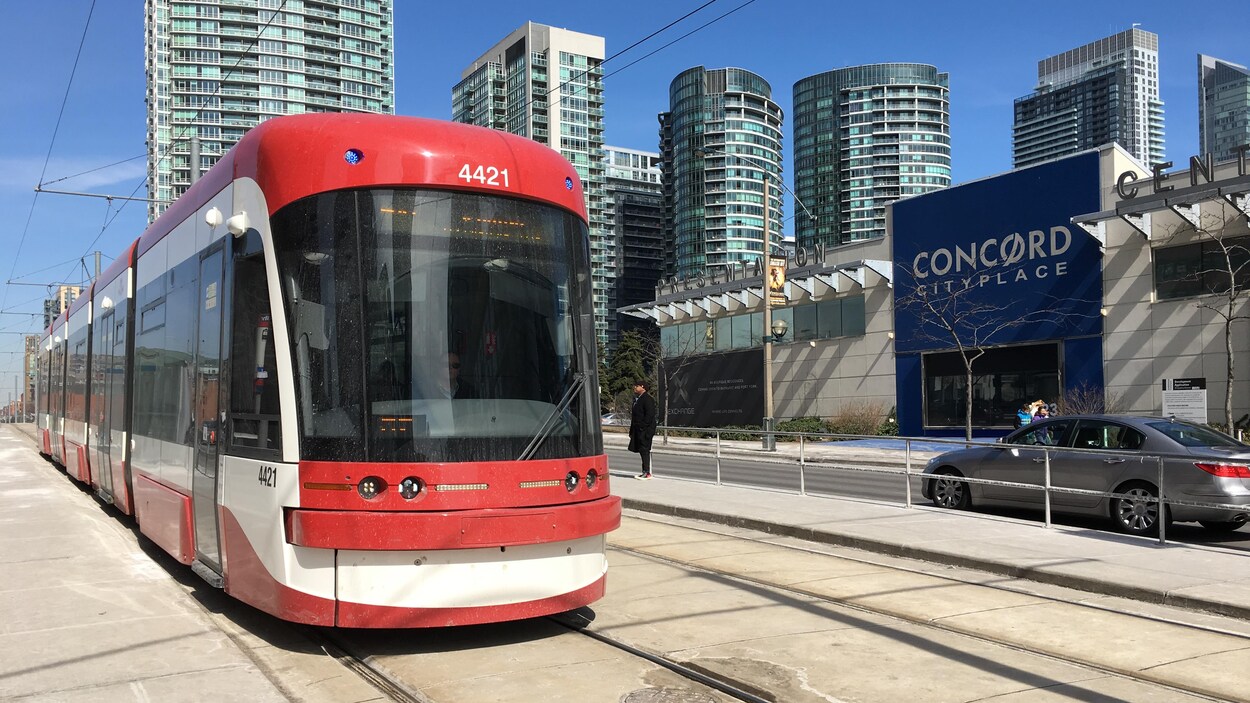 Photo d'un nouveau tramway qui roule sur l'avenue Spadina avec des tours de condos en arrière-plan Photo d'un nouveau tramway qui roule sur l'avenue Spadina avec des tours de condos en arrière-plan