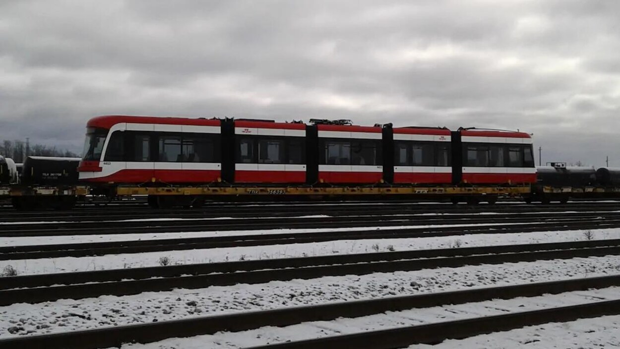 Un tramway chargé sur un train dans une gare de triage.