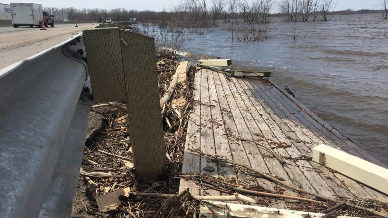 Les débris du patio flottent à côté du garde-fou de la route